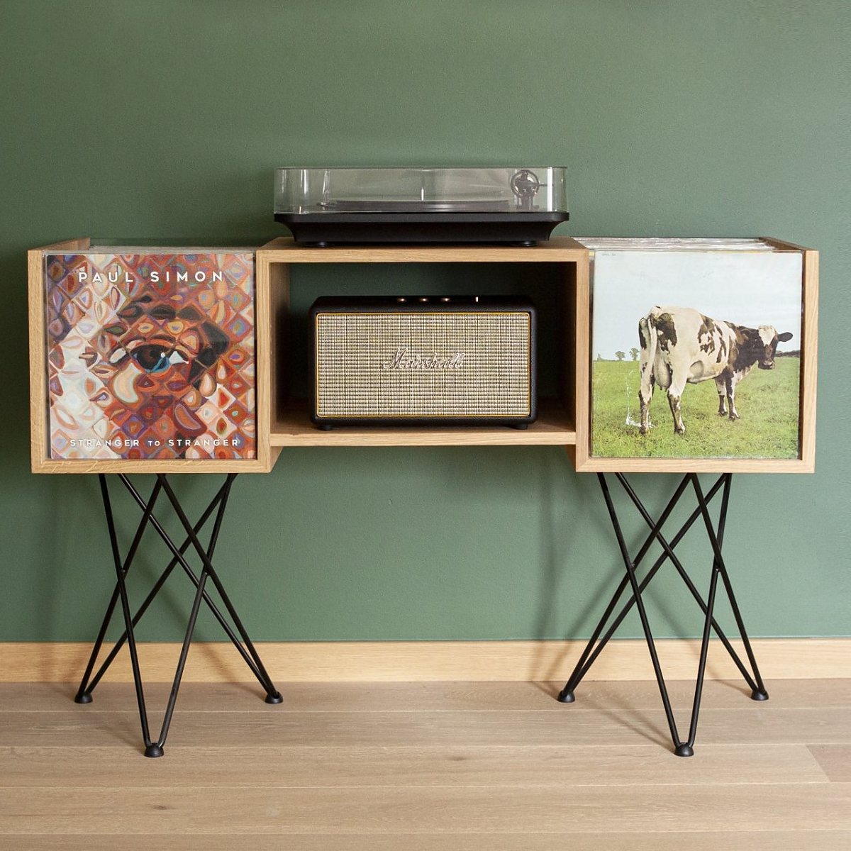 Meuble vinyle en chêne massif avec platine, enceinte et deux bacs disquaires, devant un mur vert