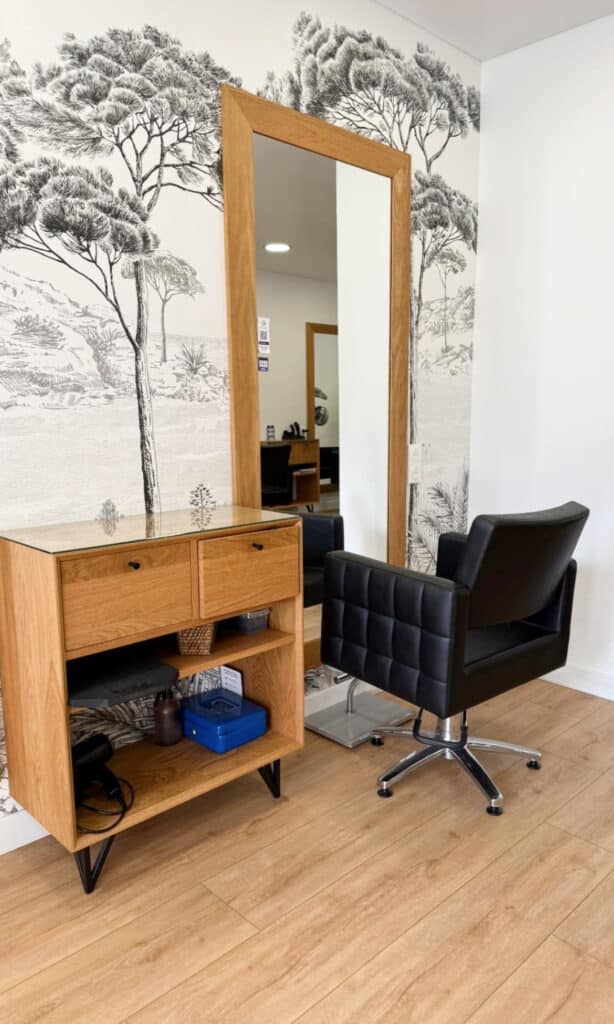 Meuble de rangement en bois clair avec étagères et tiroirs, placé dans un salon de coiffure moderne.
